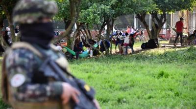 Tentara Kolombia berjaga-jaga di samping orang-orang yang mengungsi akibat pertempuran antara kelompok-kelompok bersenjata di Tibu, Norte de Santander, Kolombia (Schneyder Mendoza / AFP)